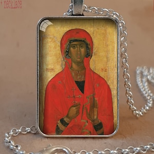 Puede incluir: Collar con bisel de plata antigua con un colgante de icono religioso. El colgante muestra una figura con t&uacute;nica roja, sosteniendo una cruz. El collar tiene una cadena y un cierre de plata. El texto en la imagen dice "Antique Silver bezel + necklace".