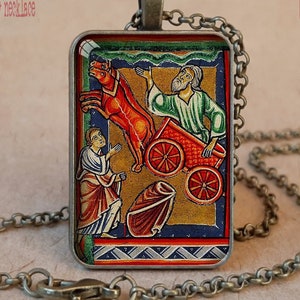 Pode incluir: Colar com moldura em bronze antigo e pingente retangular com uma ilustra&ccedil;&atilde;o religiosa colorida. O pingente mostra figuras com uma carruagem puxada por cavalos. A corrente e o fecho tamb&eacute;m s&atilde;o em bronze antigo. O texto "Antique Bronze bezel + necklace" &eacute; vis&iacute;vel.