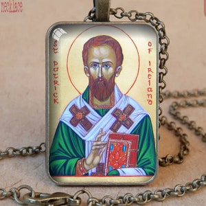 May include: Antique bronze necklace featuring a rectangular pendant with an image of St. Patrick. The pendant has a gold background and a portrait of St. Patrick in green and white robes, holding a book. The text "St. Patrick of Ireland" is visible.