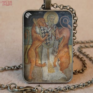 Puede incluir: Collar con colgante de bronce antiguo. El colgante rectangular presenta una imagen religiosa con leones, en colores cálidos. El colgante cuelga de una cadena a juego, creando una joya clásica y detallada.