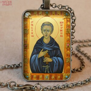 May include: Antique bronze pendant necklace with a religious icon. The rectangular pendant shows a saint with gold details, blue robes, and the text "St. Palladius, Bishop of Ireland." The necklace has a chain and clasp.