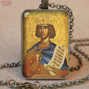 May include: Antique bronze pendant necklace featuring a religious icon with a gold halo and crown. The rectangular pendant displays a figure holding a scroll. The necklace has a chain and clasp. The text "CHRISTIAN PENDANTS" is visible.