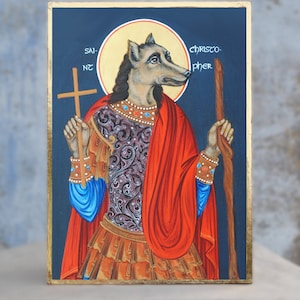 Könnte beinhalten: Gemalte Ikone des Heiligen Christophorus mit Wolfskopf, der ein Kreuz und einen Stab hält. Das Kunstwerk zeigt einen goldenen Heiligenschein, einen roten Umhang und eine verzierte Rüstung. Der Text auf der Ikone lautet "SAINT CHRISTOPHER". Die Größe ist A5, 148x210 mm.