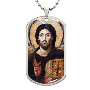 May include: A silver dog tag pendant featuring a religious icon of a man with a halo, dark hair, and a beard. The pendant hangs from a silver ball chain. The icon depicts the man holding a book.