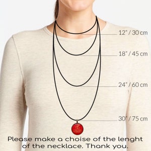 Puede incluir: Una mujer lleva un collar negro con un colgante rojo. La imagen muestra el collar en diferentes longitudes: 30 cm, 45 cm, 60 cm y 75 cm. El colgante tiene el texto "CHRISTIAN PENDANTS".
