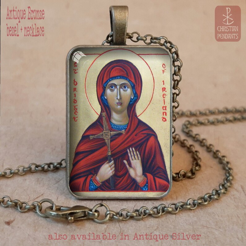 Puede incluir: Collar con colgante de bronce antiguo con un icono religioso de Santa Br&iacute;gida de Irlanda. El colgante rectangular muestra un retrato de una mujer en tonos rojos y dorados, sosteniendo una cruz. La cadena y el bisel son de bronce antiguo.