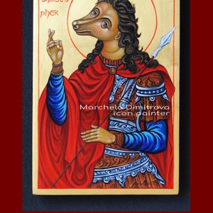 Puede incluir: Icono bizantino de San Crist&oacute;bal. La figura, con cabeza de perro, lleva una capa roja y una armadura azul y plateada. El fondo es dorado, con el texto "SAINT CHRISTOPHER".