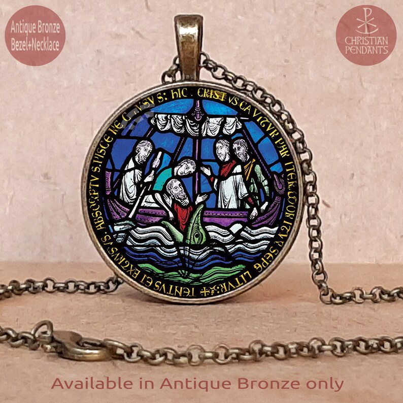 May include: Antique bronze pendant necklace with a circular, stained-glass style image of a boat and figures. The pendant displays a religious scene in blue, purple, and white. The necklace has a matching chain and clasp.