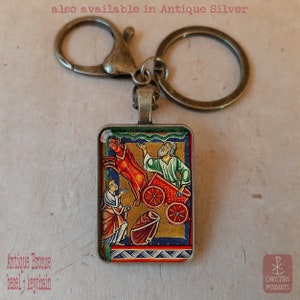 Pode incluir: Porta-chaves em bronze antigo com um pendente retangular com uma ilustra&ccedil;&atilde;o religiosa colorida. O pendente retrata uma cena b&iacute;blica com figuras, uma carro&ccedil;a puxada por cavalos e o texto "Christian Pendants". Tamb&eacute;m dispon&iacute;vel em prata antiga.
