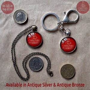 May include: A pendant necklace and keychain with a red and gold Christian symbol on a red background. The text "CHRISTIAN PENDANTS" is below the symbol. The image also includes a coin, a quarter, and a 50-cent euro coin. Available in Antique Silver & Antique Bronze.