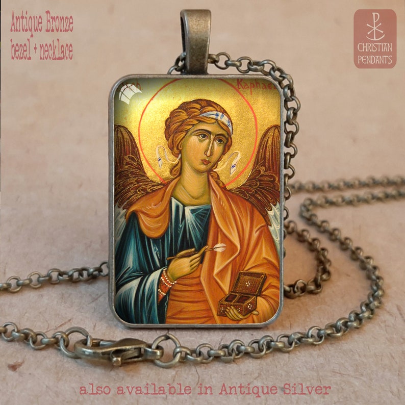 May include: Antique bronze bezel necklace featuring a religious icon of an angel with a gold halo. The rectangular pendant has a detailed image of the angel holding a small box and a tool. The necklace is on a chain.