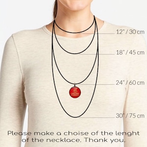 Puede incluir: Un collar con colgante rojo con un emblema dorado y el texto "CHRISTIAN PENDANTS". La imagen muestra el collar en diferentes longitudes: 30 cm, 45 cm, 60 cm y 75 cm. El texto pide elegir la longitud.