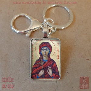 Puede incluir: Llavero plateado con un colgante rectangular que presenta un icono religioso de una mujer en rojo y dorado. La imagen incluye el texto "OF IRELAND" y "bridget". El llavero tiene un mosquet&oacute;n y un llavero.