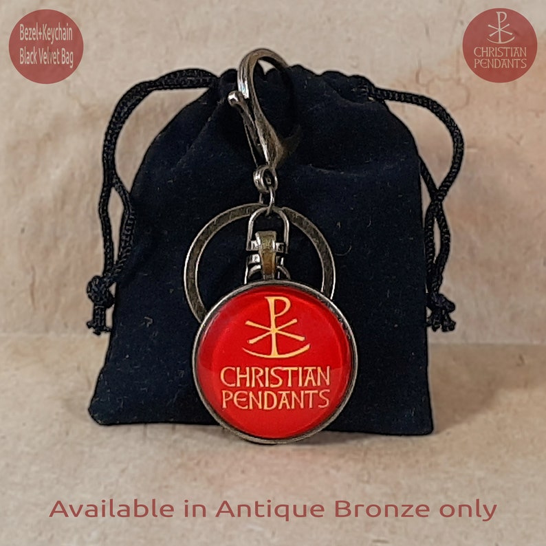 May include: A red Christian pendant keychain with gold lettering and a symbol, attached to a metal clasp and ring. The keychain is presented in a black velvet bag. The text "CHRISTIAN PENDANTS" is visible.