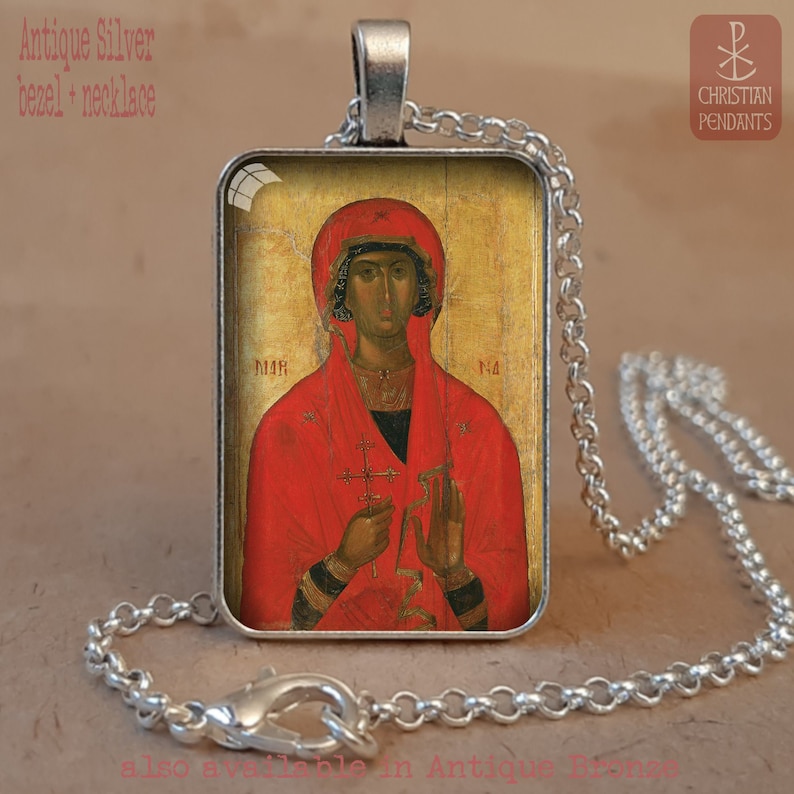 Puede incluir: Collar con bisel de plata antigua con un colgante de icono religioso. El colgante muestra una figura con t&uacute;nica roja, sosteniendo una cruz. El collar tiene una cadena y un cierre de plata. El texto en la imagen dice "Antique Silver bezel + necklace".