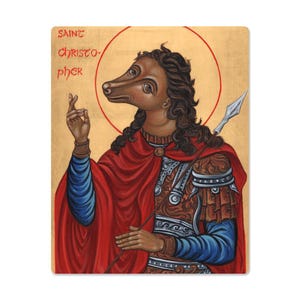 May include: Rectangular print featuring Saint Christopher with a dog-like face, wearing a red cloak and holding a spear. The text "SAINT CHRISTOPHER" is printed at the top in a stylized font. The background is a golden color with a red halo.