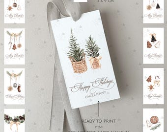 Könnte beinhalten: Satz von 10 druckbaren Geschenkanhängern mit Aquarell-Illustrationen von winterlicher Pflanzenwelt, Ornamenten und anderen Weihnachtsdekorationen. Jede Karte ist 5 cm x 9 cm groß und enthält den Text "Frohe Weihnachten".