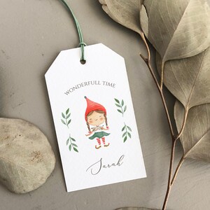 May include: A white gift tag with a green string attached. The tag features a watercolor illustration of a girl wearing a red hat and green dress. The text "Wonderfull Time" is printed above the illustration and the name "Sarah" is written below.