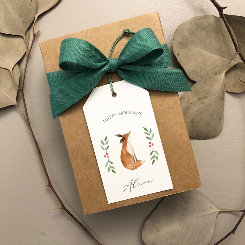 May include: A brown gift box with a green bow and a gift tag. The tag has a watercolor illustration of a fox with the text "Happy Holidays" and "Alison".