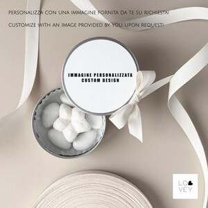 May include: A small, open silver tin filled with white candies, topped with a white lid and a white bow. The lid has the text "IMMAGINE PERSONALIZZATA CUSTOM DESIGN". White ribbon is draped around the tin. The text "CUSTOMIZE WITH AN IMAGE PROVIDED BY YOU UPON REQUEST!" is visible.
