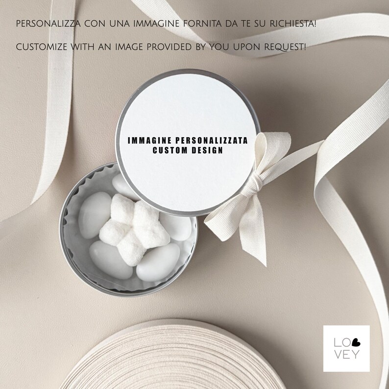 May include: A small, open silver tin filled with white candies, topped with a white lid and a white bow. The lid has the text "IMMAGINE PERSONALIZZATA CUSTOM DESIGN". White ribbon is draped around the tin. The text "CUSTOMIZE WITH AN IMAGE PROVIDED BY YOU UPON REQUEST!" is visible.