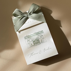 May include: A rectangular white card featuring a sage green ribbon bow at the top. The card displays a green line drawing of a building, the text March 14, 2026, and the names Thomas & Amelia in a cursive script font printed on the white paper surface.