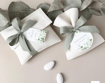 May include: Two white fabric favor bags with green ribbon and a green and white floral design. The bags are tied with a bow and have a tag with the names Allison & Michael and the date 19 August 2023.