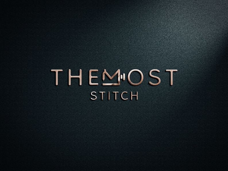 Puede incluir: Logotipo en oro rosa sobre un fondo texturizado azul oscuro. El logotipo dice "THE MOST STITCH" con un icono de m&aacute;quina de coser que reemplaza la "M" en "MOST". El logotipo tiene una apariencia met&aacute;lica tridimensional.