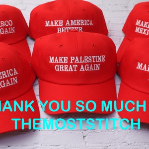 May include: Red baseball caps with white embroidered text. The caps display various phrases, including "MAKE AMERICA BETTER," "MAKE PALESTINE GREAT AGAIN," and "MAKE AMERICA EXOTIC AGAIN." The image also includes the text "THANK YOU SO MUCH !! :) THEMOSTSTITCH."