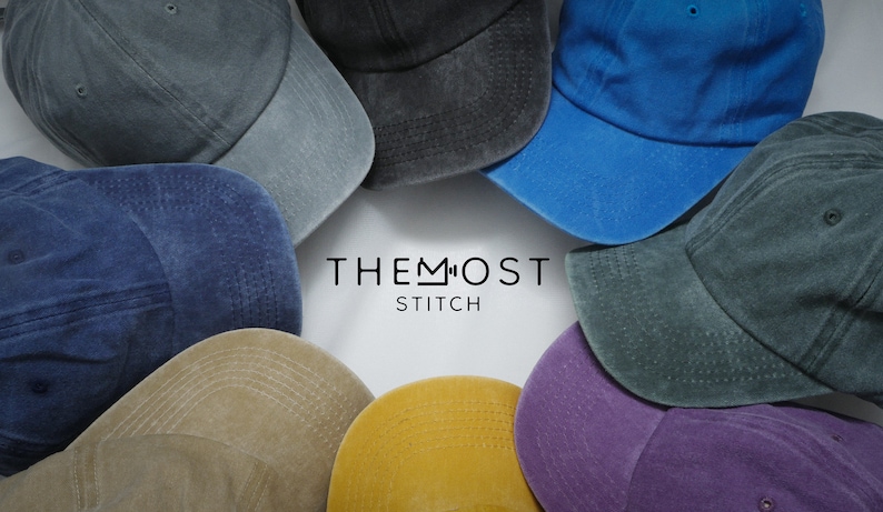 May include: A collection of baseball caps in various colors, including blue, gray, and yellow, arranged in a circular pattern. The caps have a worn, vintage look. The text "THE MOST STITCH" is centered in the image.