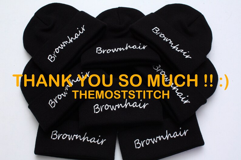 May include: A stack of black beanies with white embroidered text that reads "Brownhair" and "THEMOSTSTITCH".