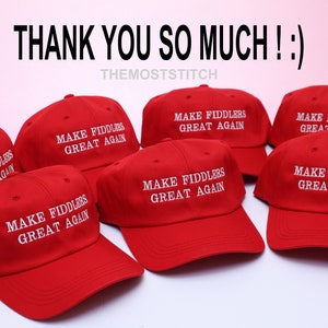 May include: Red baseball caps with the text "MAKE FIDDLERS GREAT AGAIN" in white. The caps are arranged in a group, with the text "THANK YOU SO MUCH ! :)" at the top. The shop name "THEMOSTSTITCH" is also visible.