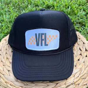 May include: Black trucker hat with a white patch featuring the state of Tennessee with a checkered pattern and the text "VFL" in black.