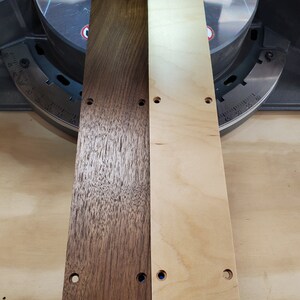 Puede incluir: Dos tablas de madera, una te&ntilde;ida de marr&oacute;n oscuro y la otra de madera natural, con varios agujeros perforados. Las tablas se colocan una al lado de la otra sobre una superficie azul.