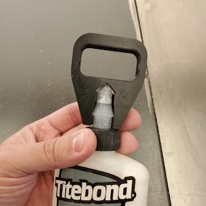 May include: A black 3D printed bottle opener designed to fit a bottle of Titebond Speed Set Wood Glue. The bottle is white with black text and a yellow and black speed gauge graphic.