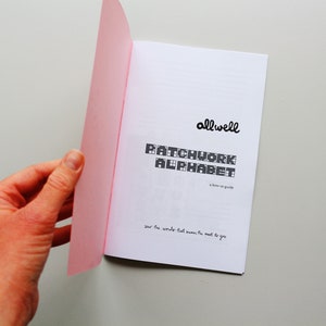 May include: A pink and white booklet with the title "Patchwork Alphabet" and the text "allwell" in a handwritten font. The text "a home-made guide" is also included. The booklet is open to reveal a page with the text "your five words that mean the most to you".