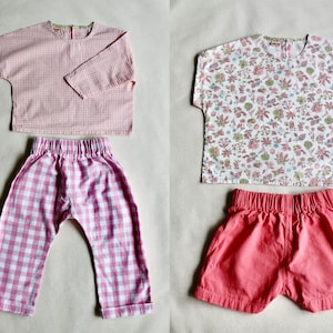 May include: Two sets of children's clothing. One set includes a pink and white gingham long-sleeve top and matching pants. The other set features a floral print top and coral shorts. Both sets have elastic waistbands.