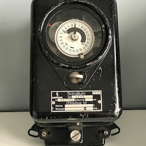 Puede incluir: Un temporizador Siemens Schaltuhr negro con una esfera blanca y una esfera plateada. El temporizador está etiquetado como "Schaltuhr" y "U2 Hz" y tiene un número de serie "548769".