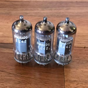 May include: Three vintage Philips EL42 vacuum tubes with silver caps and black lettering.
