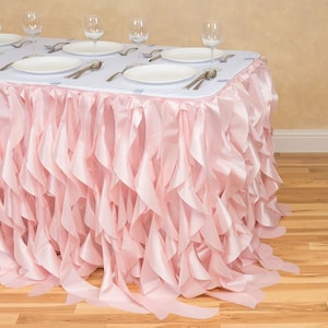 May include: A pink table skirt with multiple layers of ruffles. The skirt is made of a soft, silky fabric and is perfect for adding a touch of elegance to any table.