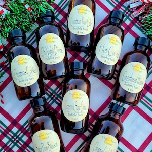 May include: Nine small brown glass bottles with black lids and white labels. Each bottle contains a different Christmas-themed bubble bath. The labels feature the name of the scent, "Harvest Moon Cottage", and the size, 4 oz.