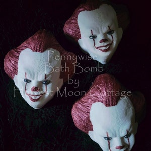 May include: Three bath bombs shaped like Pennywise the clown from the movie IT. The bath bombs are white with red glitter and have a red and white clown face painted on them. The text "Pennywise Bath Bomb by Harvest Moon Cottage" is written on the image.