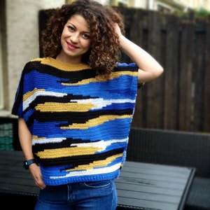 May include: A blue, black, white, and yellow crocheted top with a loose fit and short sleeves.