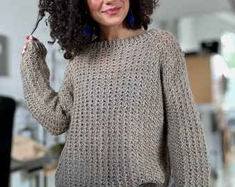 May include: A beige knitted sweater with a loose fit and long sleeves. The sweater has a textured pattern and is made of a soft, lightweight yarn.