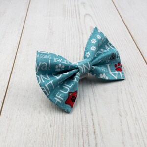 May include: A light blue bow tie with white paw prints and text that says "I love my fur baby" and "Wagging, running, playing, snuggling & being loved".
