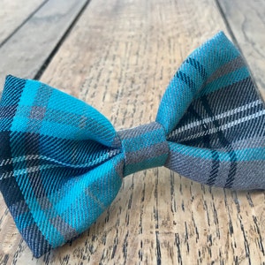 May include: A blue and grey plaid bow tie. The bow tie is made of a soft, woven fabric.