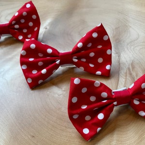 May include: Three red bow ties with white polka dots. The bow ties are made of fabric and have a simple design.