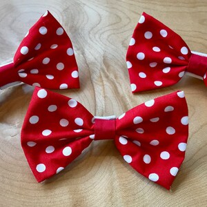 May include: Three red bow ties with white polka dots. The bow ties are made of fabric and have a simple design.