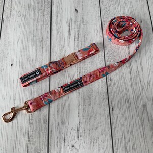 May include: A floral dog collar and leash set. The set features a peach-colored background with a colorful floral pattern. The collar has a rose gold buckle, and the leash has a matching rose gold clasp. The brand name "Abies Boutique" is printed on the collar and leash.
