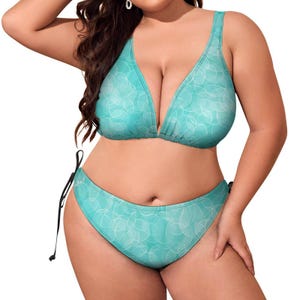 May include: A turquoise bikini set with a white, abstract pattern. The top features a V-neck design, and the bottoms have adjustable side ties. The swimwear is designed for a comfortable fit.
